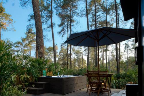 a patio with a tub and a table and an umbrella at Bobocabin Cikole, Bandung in Lembang