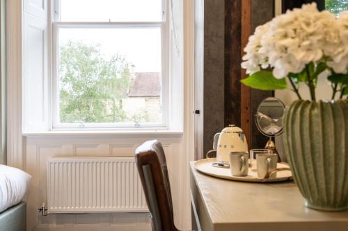 a vase of flowers on a table next to a window at Old Abbey House in Abingdon