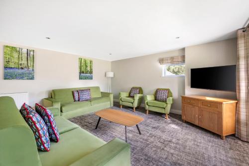 a living room with green furniture and a flat screen tv at Thurnham Hall Resort in Cockerham