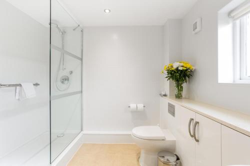 a white bathroom with a toilet and a glass shower at Thurnham Hall Resort in Cockerham
