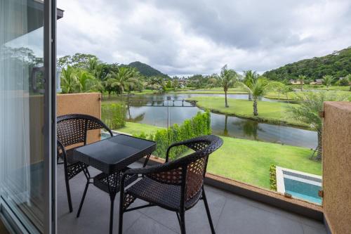 a balcony with a table and chairs and a view of a river at Utalay Koh Chang Villas in Ko Chang