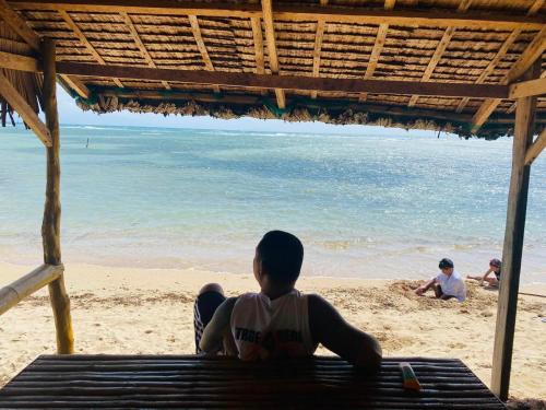 a man sitting on a bench on the beach at Beach Front Calatagan Apartelle in Calatagan