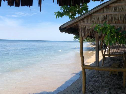 a beach with a straw hut and the ocean at Beach Front Calatagan Apartelle in Calatagan