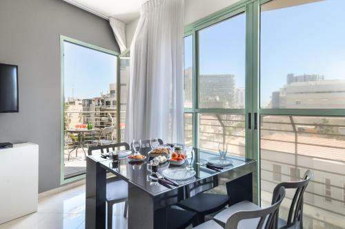 ein Esszimmer mit einem Tisch und Stühlen sowie großen Fenstern in der Unterkunft Elegant Sea-View Apartment with Mamad in the Heart of Tel Aviv by Sea N' Rent in Tel Aviv