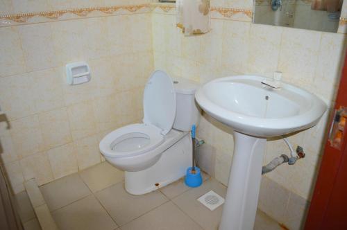 a bathroom with a toilet and a sink at Roma Stays - Elegant Apartment at Sunset Paradise with Swimming Pool & Restaurant in Mombasa