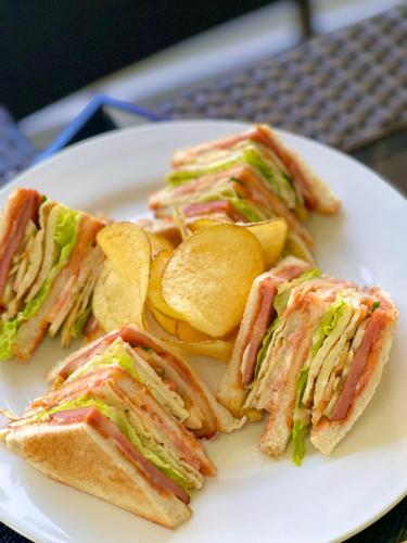 a plate with four sandwiches and chips on it at MinshukuKCS Hotel and Restaurant in Puerto Galera