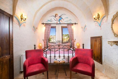 a bedroom with a bed and two red chairs at Carna Cave Hotel Cappadocia in Ortahisar