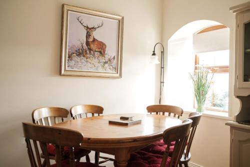 einen Esstisch mit Stühlen und ein Bild von einem Hirsch in der Unterkunft Drumnavaddy Cottage in Dromore