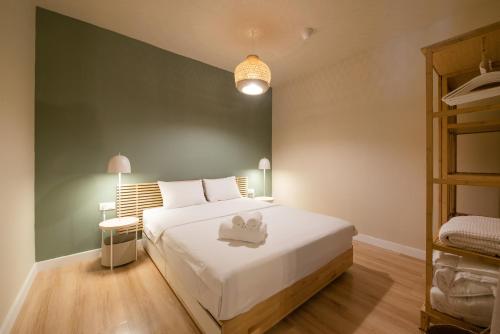a bedroom with a white bed and a green wall at Mandarin apartments by halu! in Thessaloniki