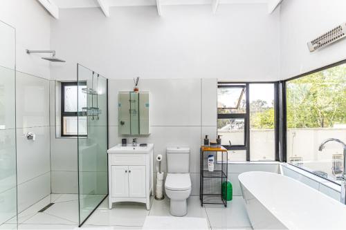 uma casa de banho com um WC, um chuveiro e uma banheira em KwaMagogo Villa, Chartwell em Joanesburgo