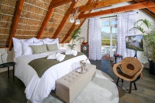 um quarto com uma grande cama branca e uma televisão em Adara Palmiet Valley Luxurious Boutique Farm Hotel em Paarl