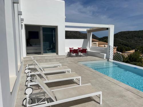 a white villa with a swimming pool and chairs at Villa Barbara in Adsubia