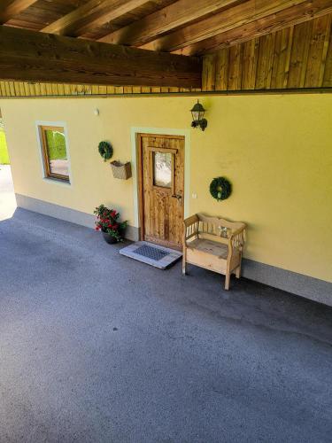 a yellow house with a wooden door and a bench at Chalet Romana in Stumm
