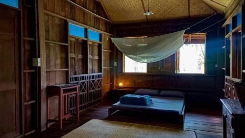 a room with a bed and a mosquito net at Traditional Lanna house near hot spring in Chiang Dao