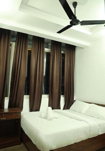 a bedroom with a bed with a ceiling fan at AROMA INN in Kalpetta