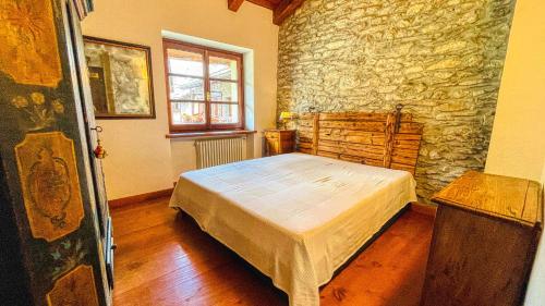 1 dormitorio con cama y pared de piedra en Appartamento Jouvenceaux 40 - Affitti Brevi Italia, en Sauze dʼOulx