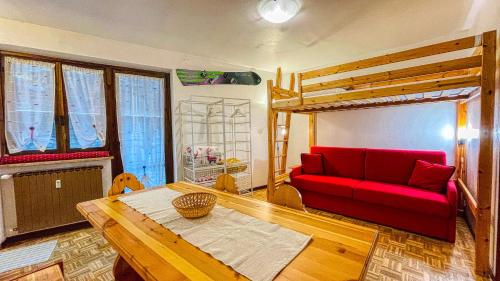 uma sala de estar com um sofá vermelho e uma cama alta em Appartamento Montana - Affitti Brevi Italia em Sauze dʼOulx