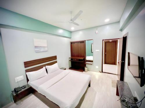 Schlafzimmer mit einem weißen Bett und einem TV in der Unterkunft Hotel Rahul Regency, Aurangabad in Aurangabad