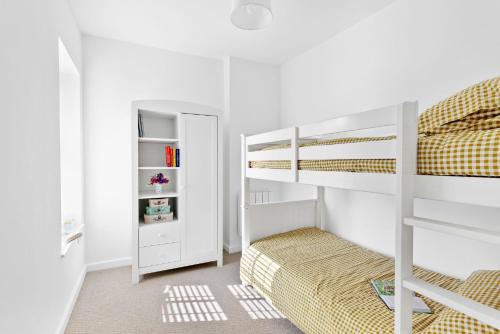 a white bedroom with a bunk bed and a book shelf at Landau Apartment, Stokenham in Stokenham