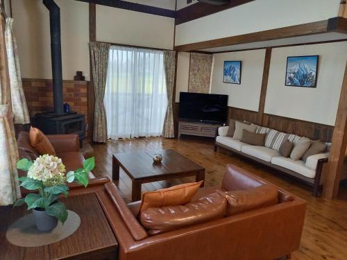 a living room with leather furniture and a fireplace at Hakuba Powder Lodge Taketombo in Hakuba