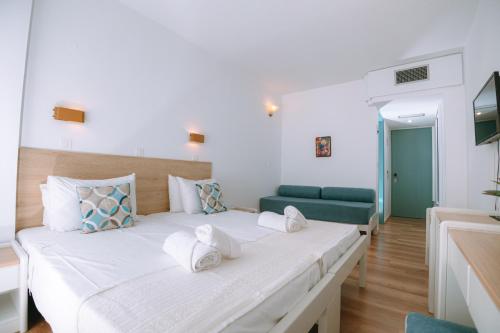 een slaapkamer met een groot bed en een groene bank bij Santa Marina Unique Hotel in Agios Nikolaos