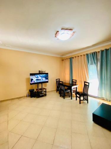 ein Wohnzimmer mit einem TV, einem Tisch und Stühlen in der Unterkunft Blessings apartment buziga in Kampala