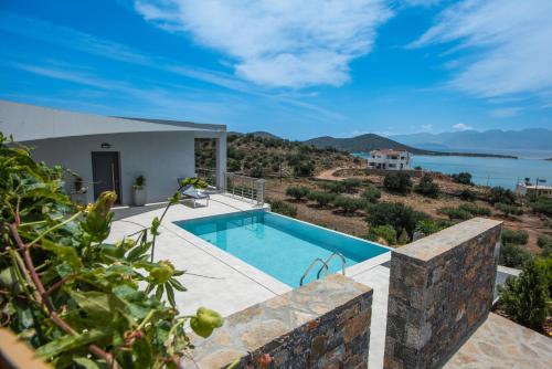 a villa with a swimming pool and a view of the water at Elounda Sunshine Place in Elounda