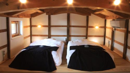 une chambre avec deux lits dans l'angle d'une pièce dans l'établissement 城崎温泉一棟貸しの宿　ゆっ蔵, à Toyooka
