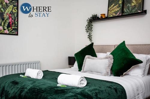 a bed with green and white sheets and towels on it at Stylish 3 bedroom property Newcastle in Kenton