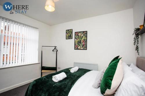a bedroom with a bed with green sheets and pillows at Stylish 3 bedroom property Newcastle in Kenton