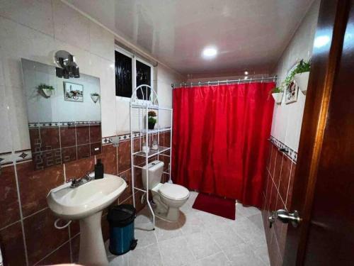 y baño con aseo y cortina de ducha roja. en Apartamento entero Tu Nido De Amor 2 Santo Domingo oeste, en Santo Domingo