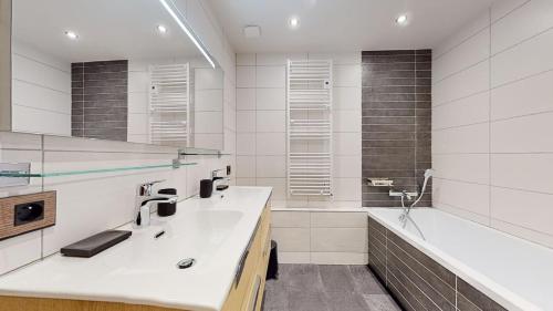 a white bathroom with a sink and a tub at Résidence Hôtelière Bellecôte 4 étoiles in La Plagne Tarentaise