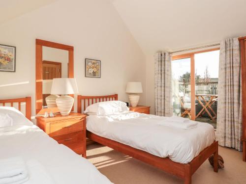 Un dormitorio con dos camas y una ventana. en 1 Court Cottage, Hillfield Village, en Dartmouth