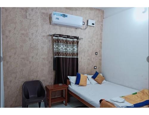 a bedroom with a bed and a chair and a window at Hotel Modern Palace, Muzaffarpur in Muzaffarpur