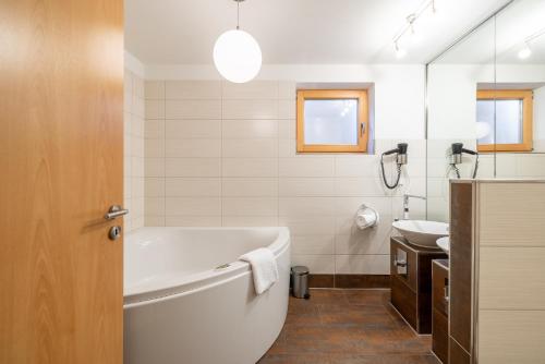 a white bathroom with a tub and a sink at Arch San Martin B in Scuol