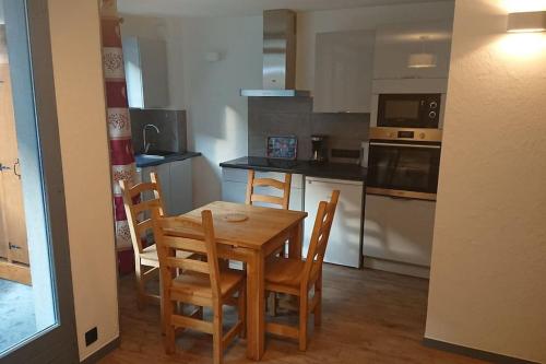 une cuisine avec une table et des chaises en bois dans l'établissement Studio au Cœur de la Tarentaise, à La Lechere