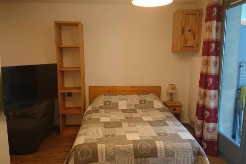 une chambre avec un lit et une télévision à écran plat dans l'établissement Studio au Cœur de la Tarentaise, à La Lechere