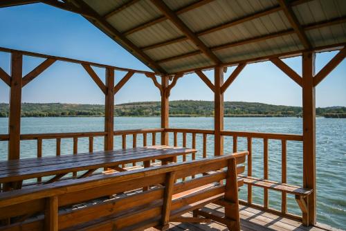 a wooden pavilion with benches on the water at Садиба на Кодимі in Archipitovka