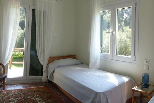 a bedroom with a bed and two windows at Pine Tree Cottage in Nea Skioni
