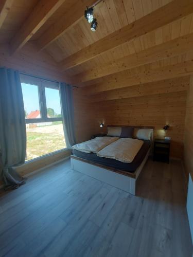 una camera da letto con un letto in una camera in legno con finestra di Haus Zielony und Haus Czerwony 