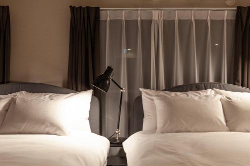 un maniquí parado entre dos camas en una habitación de hotel en Maison Roppongi, en Tokio