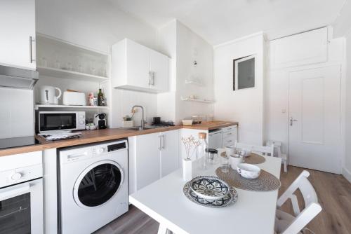 - une cuisine blanche avec une table et un lave-vaisselle dans l'établissement Angelina - Proche de la Place Bellecour, à Lyon