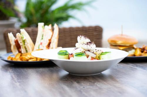 a white bowl of food on a table with plates of food at Kenta Beach Hotel in Agios Ioannis Pelio