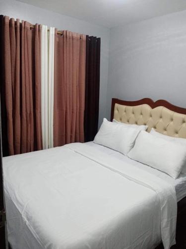 Schlafzimmer mit einem großen weißen Bett mit Vorhängen in der Unterkunft Catrionna Doll House in Tagum