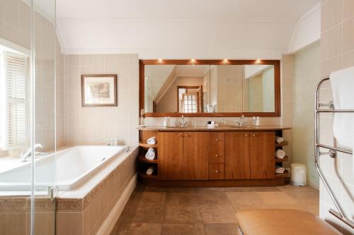 a bathroom with a tub and a large mirror at Vrede en Lust Estate in Simondium