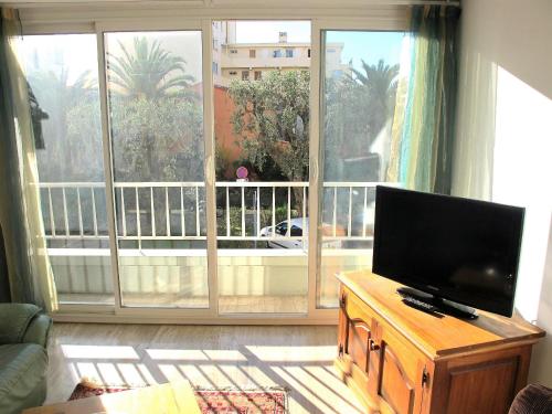 ein Wohnzimmer mit einem TV und einem großen Fenster in der Unterkunft 2 piéces bord de mer à proximité nice, antibes et monaco, 4 personnes à cros de cagnes sur mer in Cros-de-Cagnes