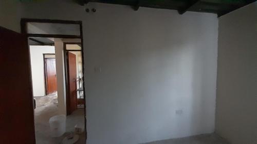 une pièce vide avec un mur blanc et une porte ouverte dans l'établissement The Warehouse, à Kitengela 