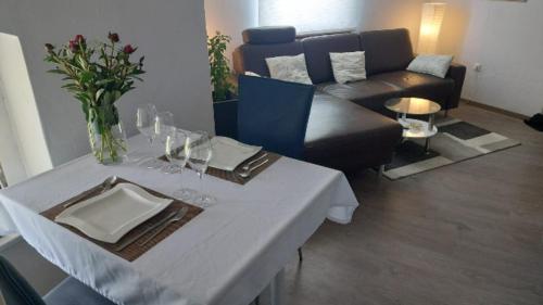 - un salon avec une table, des verres à vin et un canapé dans l'établissement Moderners Apartment am Hauptbahnhof in Minden, à Minden
