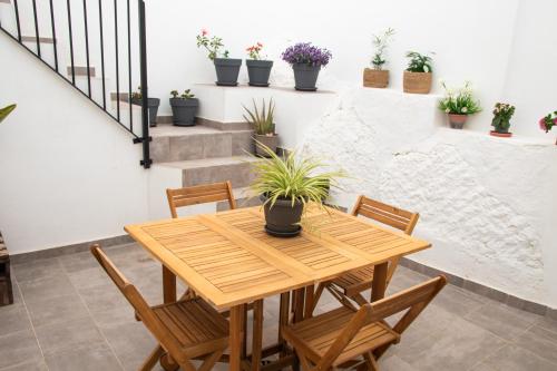 Casa Rural Los Tablaos في روت: طاولة وكراسي خشبية في غرفة مع نباتات الفخار