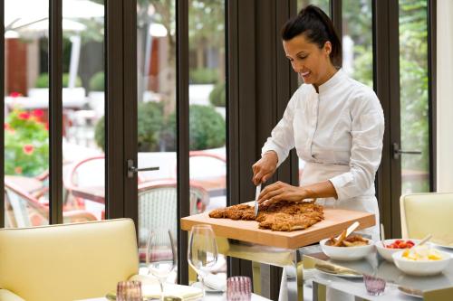 a woman preparing food on a table in a restaurant at Hôtel Le Royal Monceau Raffles Paris in Paris